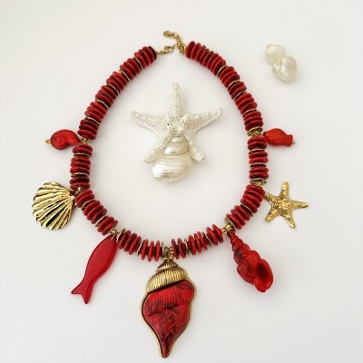 Colar com contas vermelhas e pendentes marinhos em vermelho e dourado em fundo branco