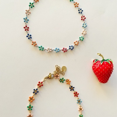 Dois colares com pequenas flores coloridas e morango decorativo