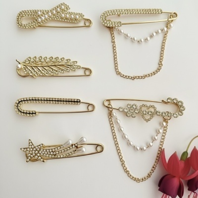 Seis alfinetes dourados com pérolas e cristais em fundo branco com flor vermelha