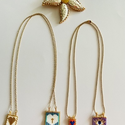 Colares com pendentes quadrados coloridos e broche flor bordado sobre fundo branco