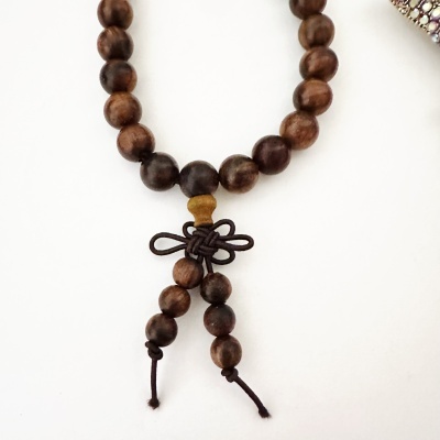 Pulseira de contas de madeira com nó decorativo em cordão castanho sobre fundo branco