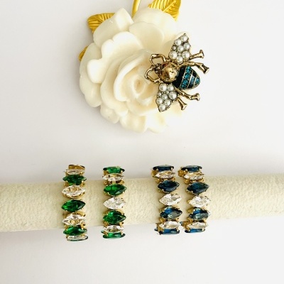 Brincos coloridos em suporte branco com anel flor e abelha decorativa