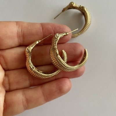 Brincos dourados em forma de argola com textura de escamas