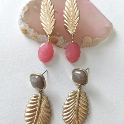 Dois pares de brincos dourados com detalhes em pedra rosa e cinzenta sobre chapa de pedra rosa e fundo branco