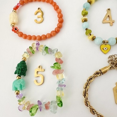 Pulseiras coloridas com pedras e pingentes sobre fundo branco.