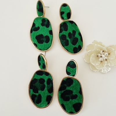 Dois pares de brincos pendentes com padrão animal verde e preto e bordas douradas junto a flor decorativa