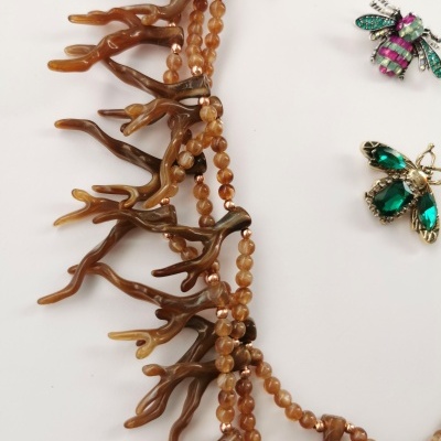 Colar castanho com pendentes em forma de coral e broches coloridos em forma de insetos