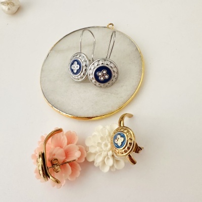Brincos com detalhe azul e floral repousando sobre flores decorativas