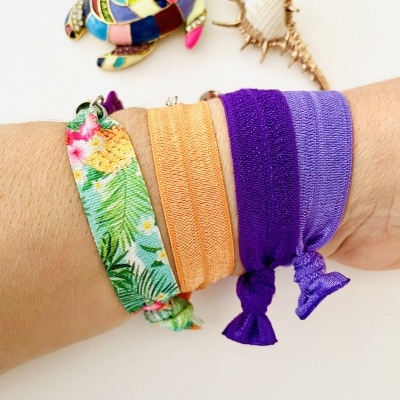 Pulseiras de tecido coloridas num pulso, com tartaruga decorativa e concha ao fundo