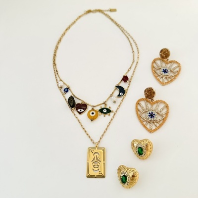 Colares dourados com pingentes diversos e brincos dourados com detalhes de olhos e pedras verdes