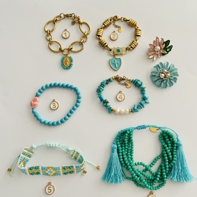Conjunto de pulseiras e flores esmaltadas em tons de turquesa e dourado sobre fundo branco