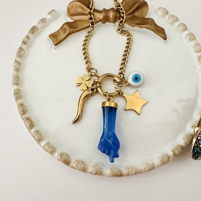 Colar dourado com vários pendentes coloridos num prato branco com borda texturizada