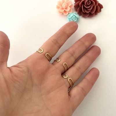 Mão com anéis dourados tipo corrente e flores decorativas coloridas