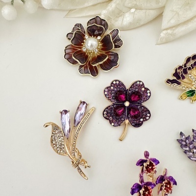 Broches florais com pedras roxas e detalhes em pérola e esmalte castanho