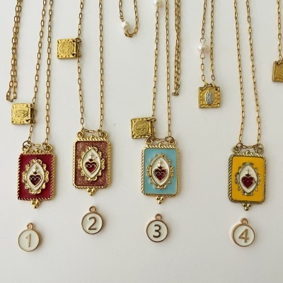 Colares dourados com pendentes retangulares coloridos e números 1 a 4 pendurados.