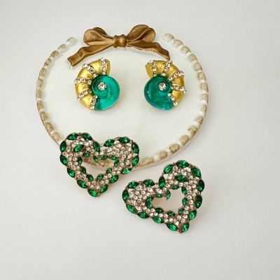 Brincos verdes e dourados com cristais em fundo branco