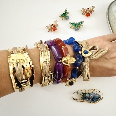 Pulseiras femininas coloridas e douradas em braço com fundo branco