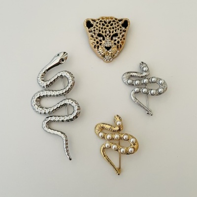 Broches metálicos de cobras com pérolas e cabeça de leopardo em fundo branco