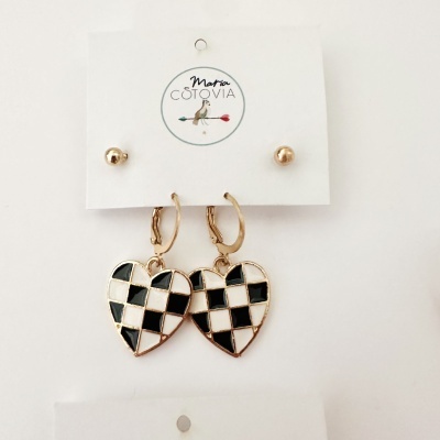 Brincos com tachas douradas e argolas com coração xadrez preto e branco em cartão com logótipo