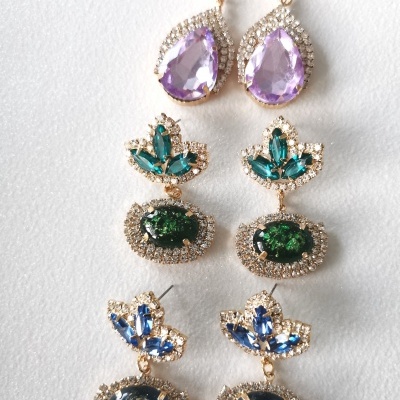 Três pares de brincos pendentes com pedras roxa, verde e azul, bordas de cristal e acabamento dourado