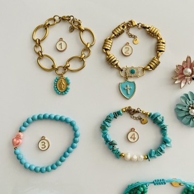 Quatro pulseiras com contas e pendentes em tons dourados e azul-turquesa em fundo branco.