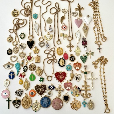 Vários colares e pendentes dourados com diferentes formatos e cores sobre fundo branco.