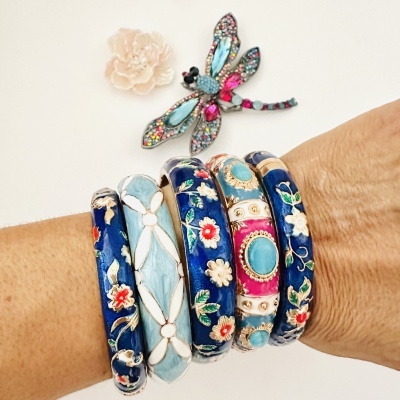 Pulseiras esmaltadas azuis com detalhes florais e broche de libélula colorida
