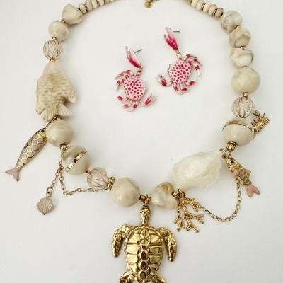 Conjunto de bijuteria com colar de contas creme e dourado e brincos de caranguejo rosa