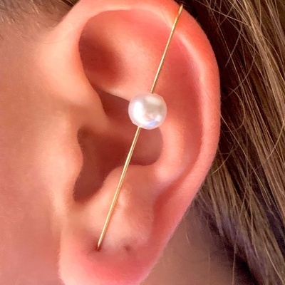 Argola dourada com pérola numa orelha humana