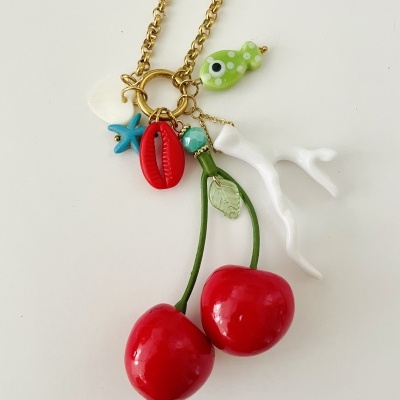 Colar dourado com pendentes de cerejas vermelhas e motivos marinhos coloridos