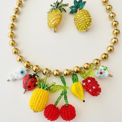 Colar dourado com pendentes de frutas e bichos coloridos e brincos em forma de ananás amarelo