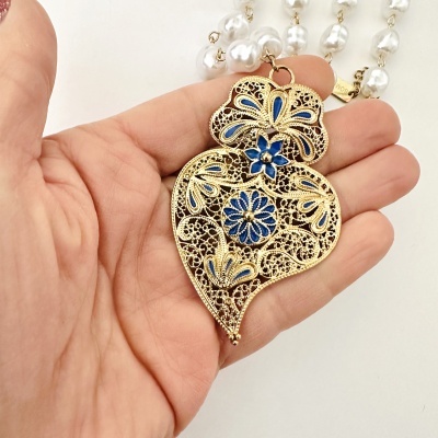 Colar com pendente metálico dourado em forma de coração com detalhes azuis e contas peroladas brancas
