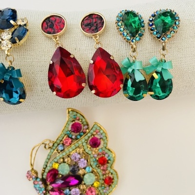 Brincos com pedras coloridas e broche de borboleta com pedras coloridas sobre fundo claro