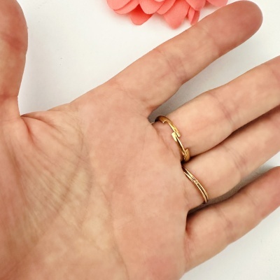 Mão com pulseiras douradas e pétalas cor de rosa ao fundo