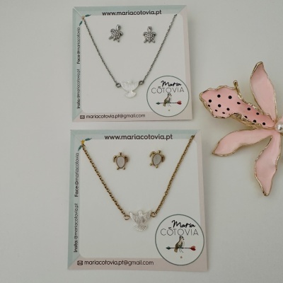 Conjunto de bijuteria com colar e brincos com pendentes de tartaruga e pomba em cartão de apresentação