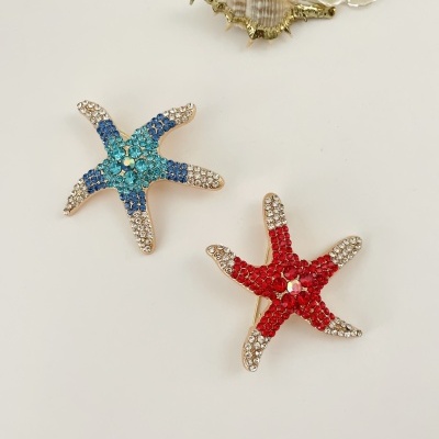 Dois broches em forma de estrela-do-mar com pedras azuis e vermelhas brilhantes