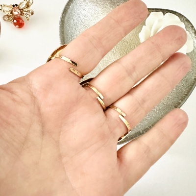 Mão com anéis dourados finos, prato cinzento e flor branca em fundo branco