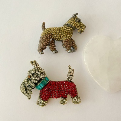Dois broches em forma de cão com pedras coloridas e uma pedra coração branca