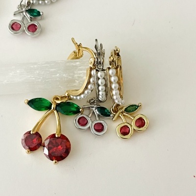 Brincos com pendentes de cereja em pedras vermelhas e verdes sobre fundo branco