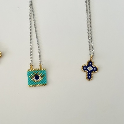 Colares com pingentes de contas em forma de olho e cruz sobre fundo branco