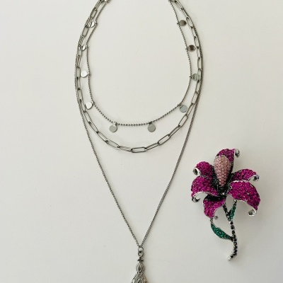 colar prateado com três correntes e broche florido com pedras coloridas