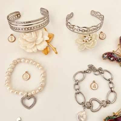 Pulseiras diversas com flores, pérolas e corações sobre fundo claro