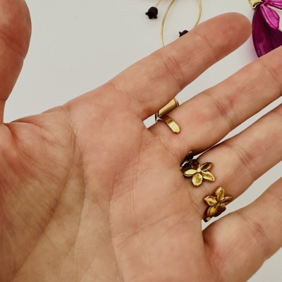 Mão com anel dourado e flores douradas sobre fundo branco