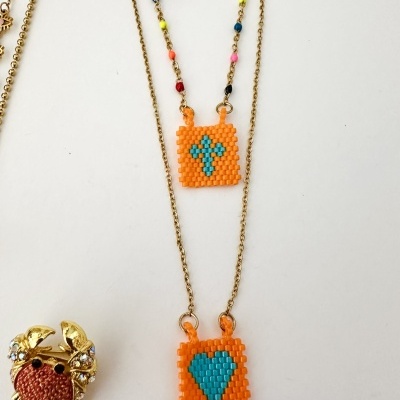 Colar com pendentes quadrados em contas laranja e anel dourado em forma de caranguejo.