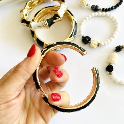 Pulseiras e braceletes pretos, brancos e dourados com detalhes florais e padrão de bambu