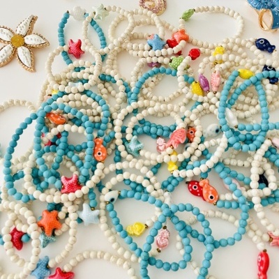 Pulseiras e brincos coloridos com motivos marinhos e pedras azuis e brancas.