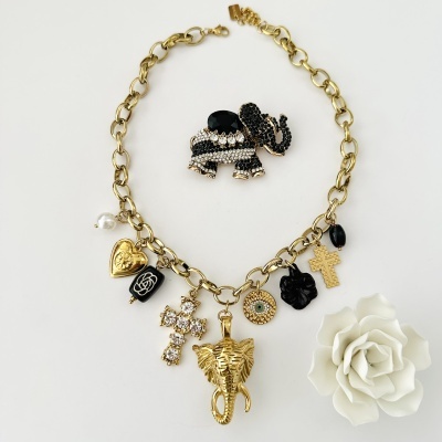 Colar dourado com pendentes diversos e broche de elefante decorado com pedras pretas e brancas