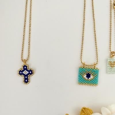 Colares com pendentes em contas coloridas em fundo branco com flor decorativa