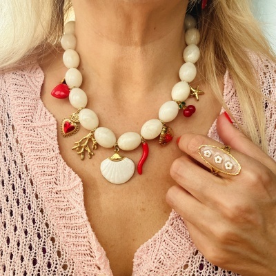 Colar creme com pendentes vermelhos e dourados e anel dourado com flores brancas