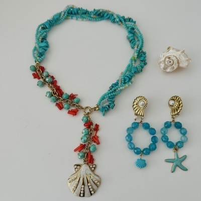 Colar de contas azuis e coral com pendente de concha dourada e pérolas, e brincos dourados com pérolas e pendentes azuis.